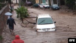 Dos mujeres avanzan entre la lluvia hoy, lunes 16 de septiembre de 2013, en Chilpancingo (México).