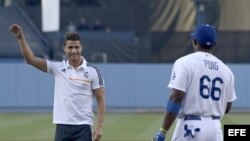 Cristiano Ronaldo (i) sonríe frente a Yasiel Puig (d) tras realizar el lanzamiento previo al inicio del juego de la MLB entre los Dodgers de Los Ángeles y los Yankees de Nueva York en el Dodger Stadium. 